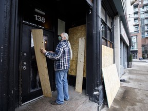 A bar owner boards up his business in Toronto, on Monday, Nov. 23, 2020 amid a new lockdown.
