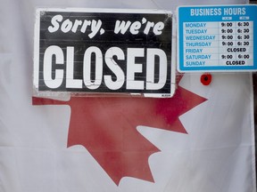 A "closed" sign hangs in a store window in Ottawa.