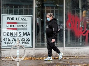 A pedestrian wearing a mask walks past a storefront for lease on Toronto’s Queen Street West in October.  Economists now expect a harder winter than was expected.
