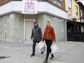 Shoppers walk past by empty stores in Toronto. It's been a year of unrelenting pain in retail, with widespread economic shutdowns toppling cornerstones of Canada's retail industry just as easily as small operations.