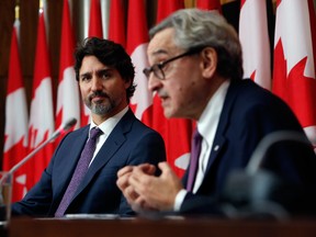 Prime Minister Justin Trudeau listens while Michael Sabia speaks during a news conference in October.
