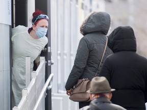 A health-care worker talks with people as they wait to be tested for COVID-19 at a clinic in Montreal.