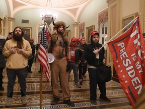 Supporters of U.S. President Donald Trump, including member of the QAnon conspiracy group Jake Angeli, aka Yellowstone Wolf, centre, enter the U.S. Capitol on Jan. 6, 2021, in Washington, D.C.