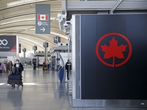 A passenger wheels his luggage near an Air Canada logo at Toronto Pearson International Airport.