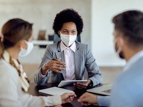 Happy African American financial advisor consulting her clients while wearing protective face mask on a meeting.