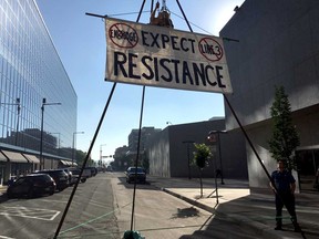 An activist opposing the Enbridge Line 3 oil pipeline, dangles from a steel structure erected outside the Minnesota Public Utilities Commission office in St. Paul, Minnesota in 2018.  While the Canadian portion is complete, Enbridge has run into repeated obstacles in this state, where reviews have lasted for about five years.