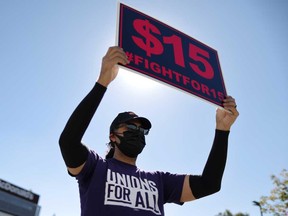 A man holds up a minimum wage sign at a rally held by fast food workers and supporters in California.