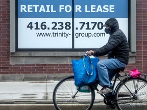 A cyclist rides past a Retail For Lease location on Queen Street East in Toronto during the COVID-19 pandemic.
