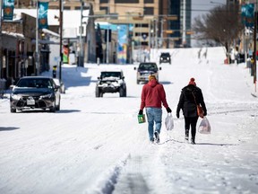 People carry groceries from a local gas station on Monday in Austin, Texas. Winter storm Uri has brought historic cold weather to Texas, causing traffic delays and power outages.