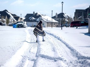 A man walks to his friend's home in a neighbourhood without electricity as snow covers the BlackHawk neighborhood in Pflugerville, Texas, U.S. February 15, 2021.