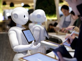 SoftBank Group Corp. Pepper humanoid robots stand behind a counter while customers place orders at the Pepper Parlor cafe in Tokyo, Japan, on Thursday, Dec. 5, 2019.