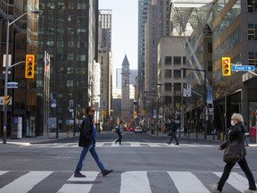 Morning commuters cross Yonge Street at Bay Street in the financial district of Toronto in May.