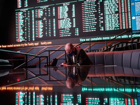 A man sits on a couch as betting odds for NFL football's Super Bowl 55 are displayed on monitors at the Circa resort and casino sports book, Wednesday, Feb. 3, 2021, in Las Vegas.