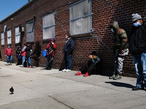 People wait in line to receive food at a food bank in Brooklyn amid the pandemic.