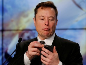 Elon Musk looks at his mobile phone.