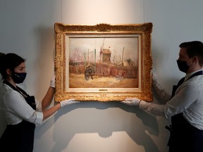 Sotheby's Paris employees pose with the 1887 painting of a Paris street scene "Scene de rue a Montmartre" by Dutch painter Vincent Van Gogh which will be presented to the public for the first time after spending more than a century behind closed doors in the private collection of a French family, France, February 24, 2021.