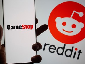A GameStop logo on a smartphone is seen in front of a displayed Reddit logo.