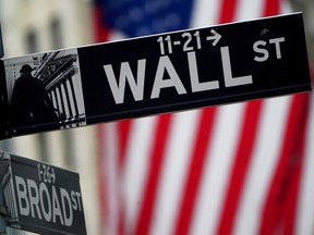 A Wall Street sign outside the New York Stock Exchange, in front of an American flag.