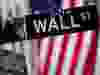 A Wall Street sign outside the New York Stock Exchange, in front of an American flag.