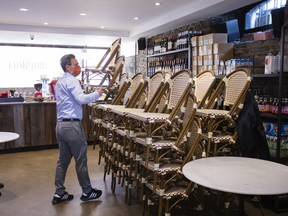 A worker wearing a protective mask stacks chairs inside a restaurant in Montreal, Quebec, Canada, on Thursday, Oct. 1, 2020.