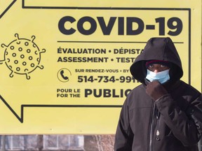 A man he walks past a COVID-19 testing clinic in February, 2021 in Montreal. Quebec and Ontario have experienced the most stringent restrictions in Canada in the later stages of the pandemic.