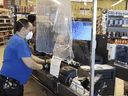 Workers install a protective shield for cashiers at a Metro store in Toronto.