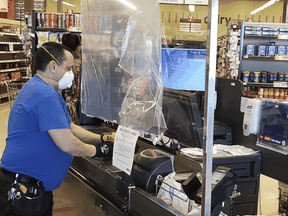 Workers install a protective shield for cashiers at a Metro store in Toronto.