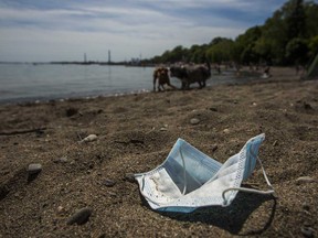 A discarded mask lies on the sand on a beach in Toronto. A year ago today the World Health Organization declared coronavirus a pandemic.