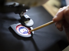 An employee arranges a logo patch in a sewing machine at a Canada Goose manufacturing facility in Montreal.