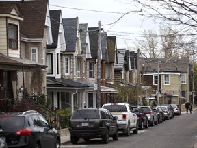 Vehicles sit parked outside a row of houses in Toronto.