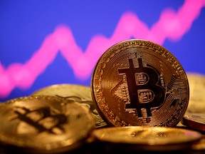 representation of virtual currency Bitcoin is seen in front of a stock graph.