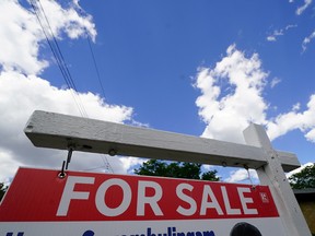 A real estate for sale sign set against a blue sky.