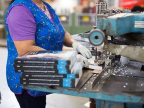 An employee uses a drill press to add holes to books at the Holmes Finishing House printing and binding facility in Markham, Ontario.