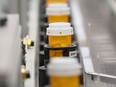 Bottles of prescription drugs are filled as they move down an automated line in a pharmacy.