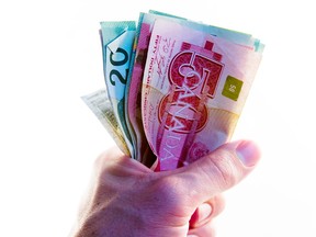 A man's fist holding Canadian cash.