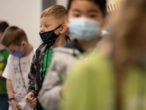 Young children in masks lined up at a school.