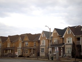 A "For Sale" sign in front of a row of homes in a subdivision in Vaughan, Ontario.