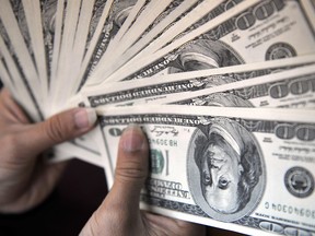 A money changer counts out U.S. 100-dollar banknotes