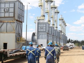 Employees at the Cenovus Christina Lake oilsands facility, located south of Fort McMurray, walk past steam generators  as they begin their shift.