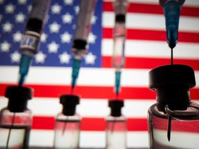 Vials and syringes are seen in front of U.S. flag in this illustration photo. If all of the world's vaccines were distributed based on population, the U.S. would have administered nearly six times its fair share.