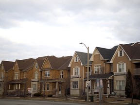 A "for sale" sign in front of a row of homes in a subdivision in Vaughan, Ont.