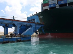 A dredger attempts to free stranded container ship Ever Given, one of the world's largest container ships, after it ran aground, in Suez Canal, Egypt March 26, 2021.