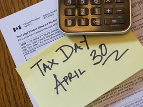 A Canada Revenue Agency tax form, a calculator and a yellow sticky note that says: Tax Day April 30.