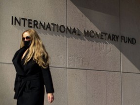 A woman walks past an International Monetary Fund headquarters(IMF) building in Washington, D.C.