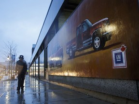 A pedestrian walks past a General Motors Co. mural depicting in downtown Oshawa, Ont.