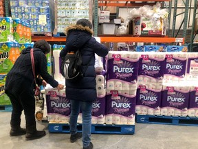 Shoppers grab toilet paper from a pallet in a Costco in Calgary.
