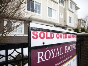 A real estate sign reading "Sold Over Asking" stands on display outside a townhouse in Richmond, British Columbia.