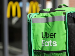 An Uber Eats food delivery courier's backpack in front of a McDonald's