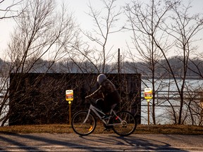 A man cycles past signposts marking the presence of Enbridge's Line 5 pipeline, which Michigan Governor Gretchen Whitmer ordered shut down in May 2021, in Sarnia, Ont.