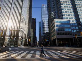 A woman crosses the street during morning commuting hours in Toronto's financial district amid the pandemic.